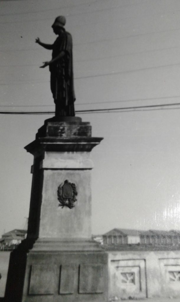 A deusa Atena, cópia da escultura da cidade de Villetri que representa a sabedoria, se coloca em posição de quem discursa à uma plateia. A mão esquerda estendida simbolizando o chamado e a mão direita apontando para o céu. NA PONTE MAURICIO DE NASSAU EM RECIFE/PE